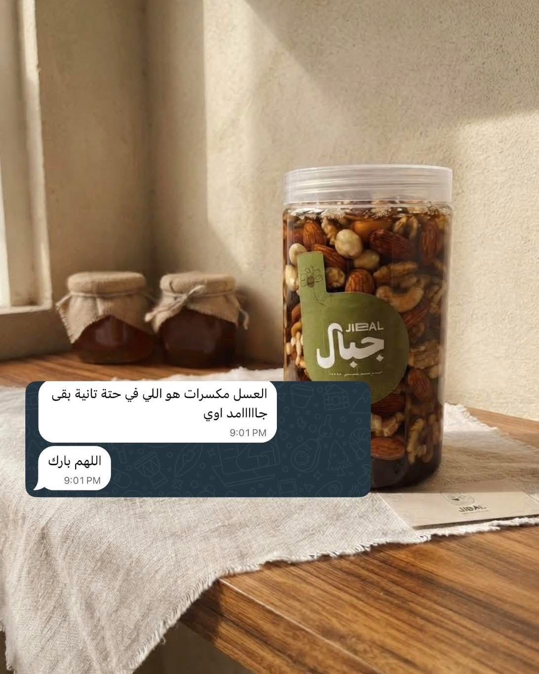 علبة مكسرات بالعسل من جِبال على طاولة خشبية مع لقطة رسائل محادثة