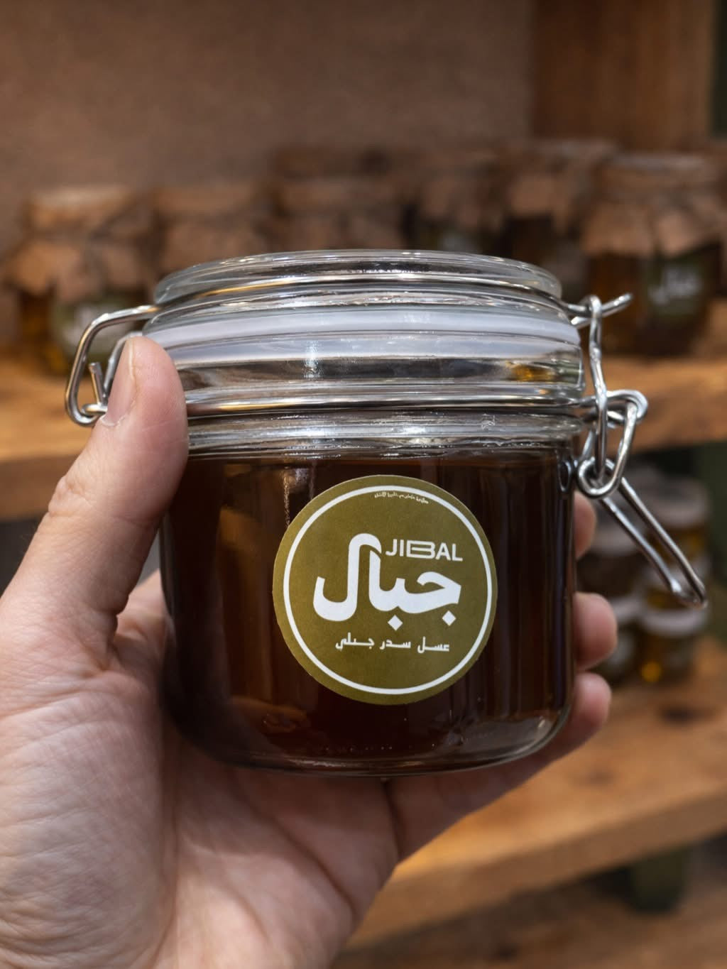 يد تحمل برطمان عسل سدر مصري من جِبال بغطاء زجاجي محكم